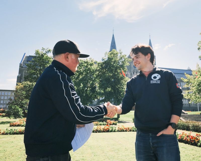 Ole Dokka og Freider Fløan håndhilser i en park etter at avtalen mellom Spaceport Norway og NORSTEC ble signert